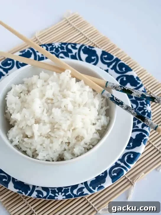 How to Cook Fluffy White Rice Every Time 4 A closeup image of a bowl of Perfect White Rice with chopsticks from themerchantbaker.com