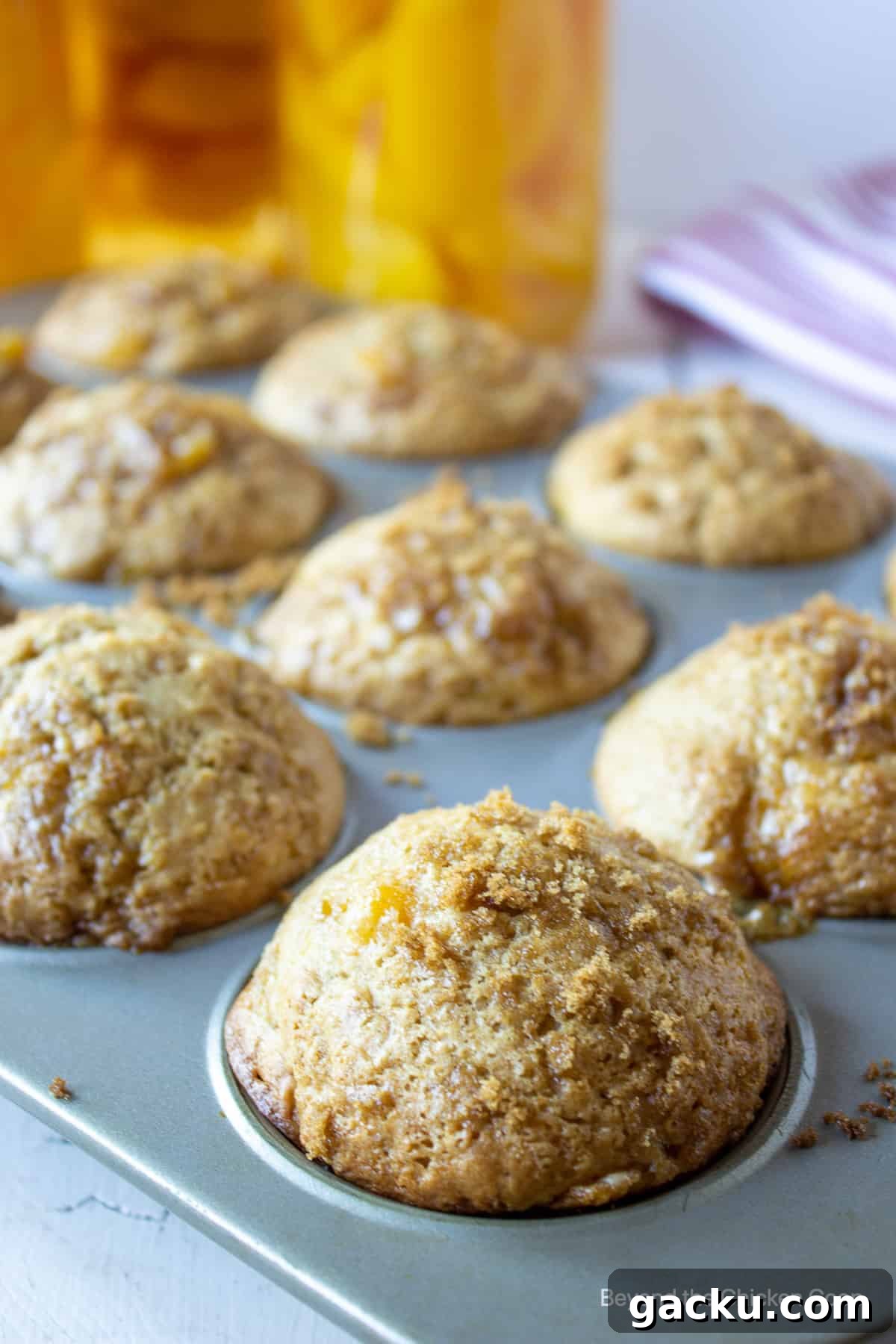 Juicy Peach Muffin Recipe for Perfect Summer Breakfast 4 Baked muffins in a muffin tin.