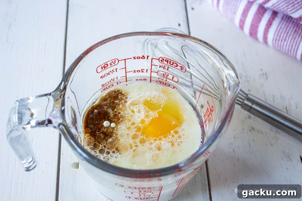 Juicy Peach Muffin Recipe for Perfect Summer Breakfast 6 A glass measuring cup with egg, milk and vanilla.