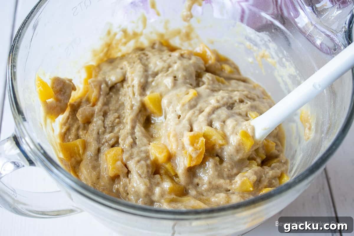 Juicy Peach Muffin Recipe for Perfect Summer Breakfast 9 Peaches in a muffin batter in a glass bowl.