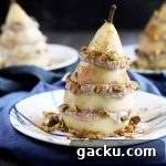 Horizontal image of a plated fruit and ricotta stack covered in nuts, with the same two plated desserts in the background on blue napkins.