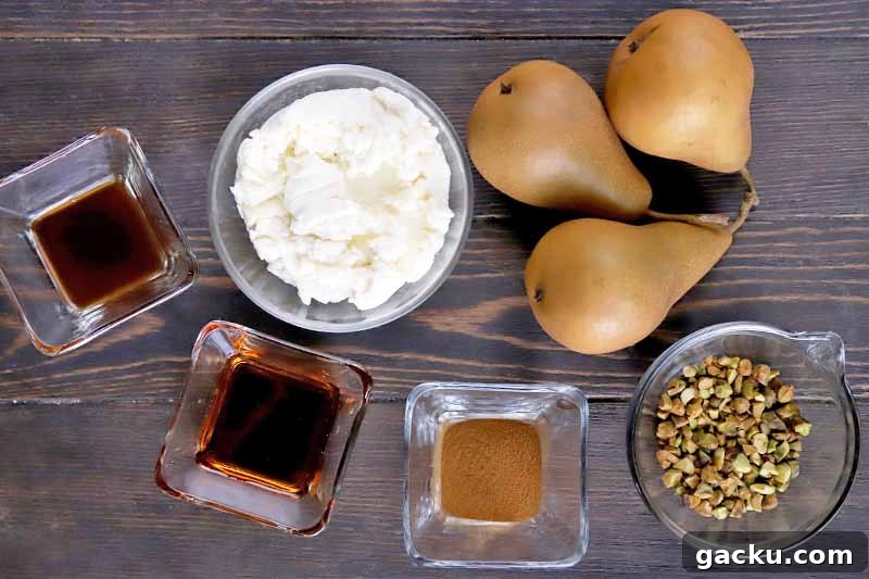 Horizontal overhead image of three small square glass dishes of vanilla, maple syrup, and ground cinnamon, and small round glass bowls of ricotta and chopped pistachios, with three brown Bosc pears on a dark brown wood surface.