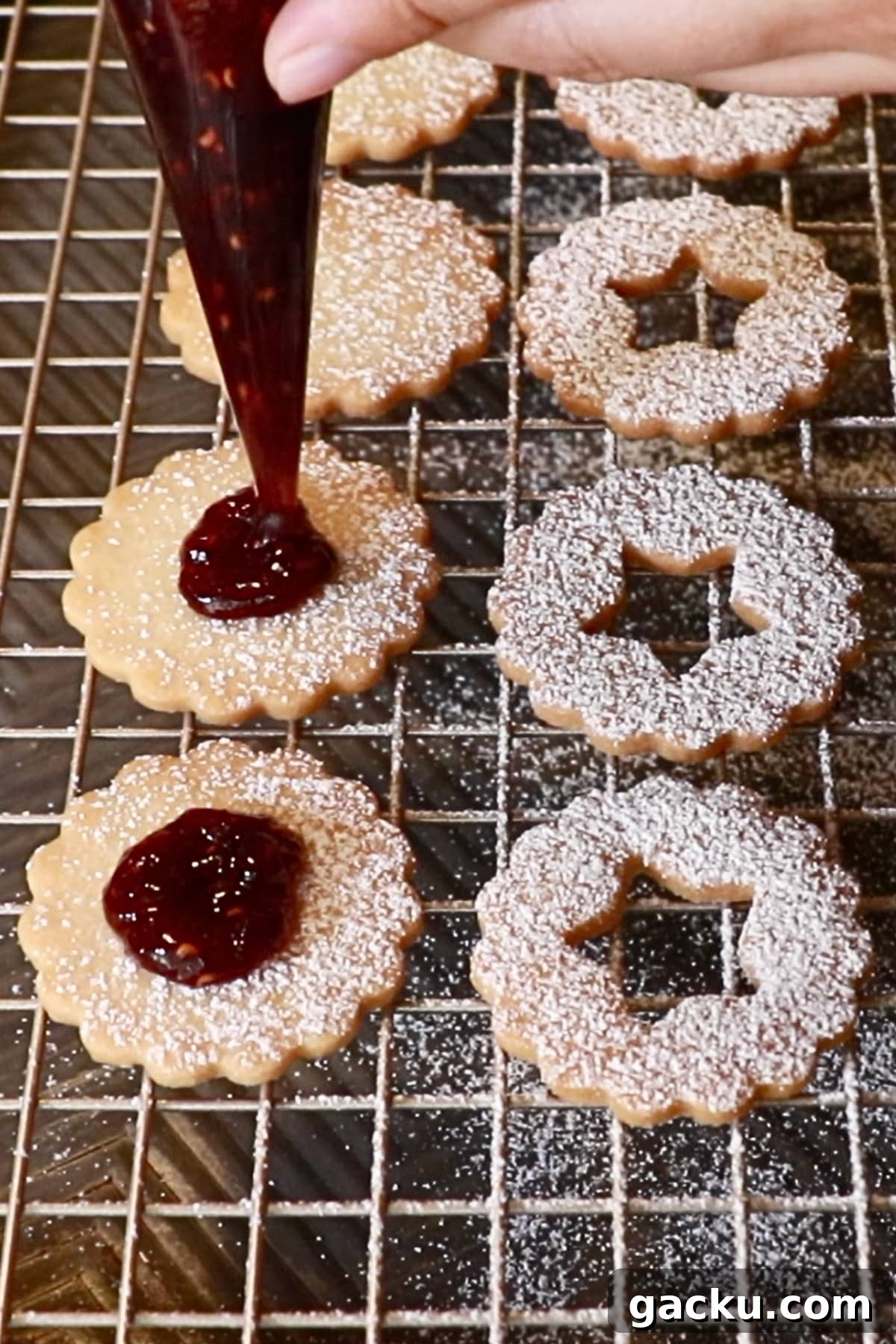 piping raspberry jam on cookies