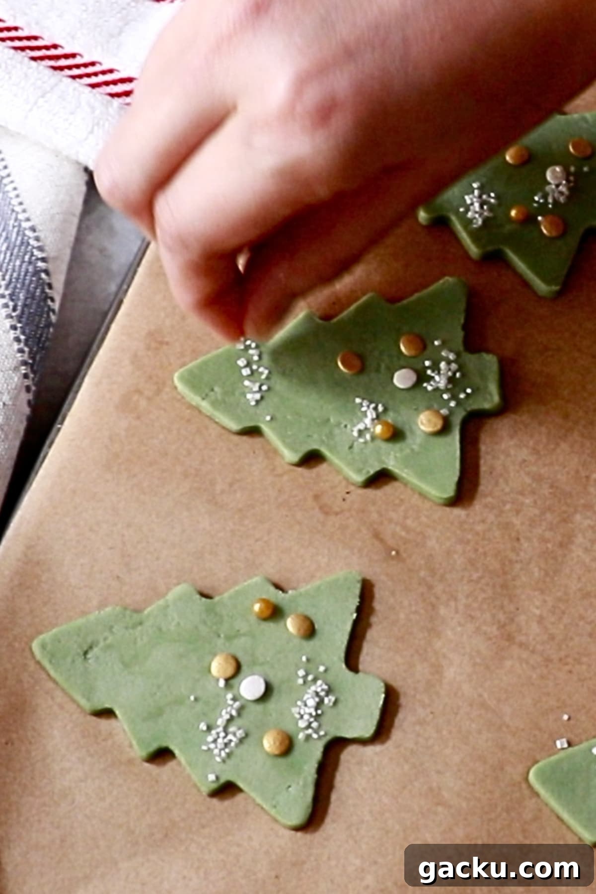 attaching sprinkles on christmas tree cookie dough