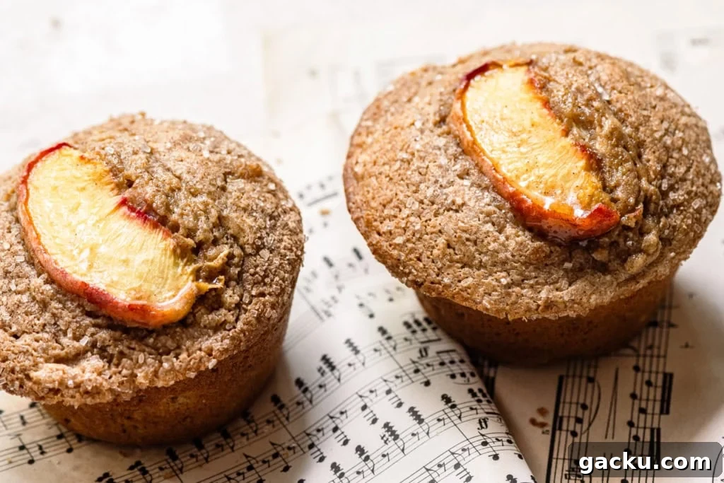 Homemade Peach Muffins with Fresh Summer Fruit 4 Two muffins topped with peach slices and sugar on music sheets of paper.