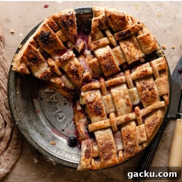 Homemade Peach Muffins with Fresh Summer Fruit 9 Overhead image of a baked pie with a lattice crust in a metal pie pan with a slice missing.