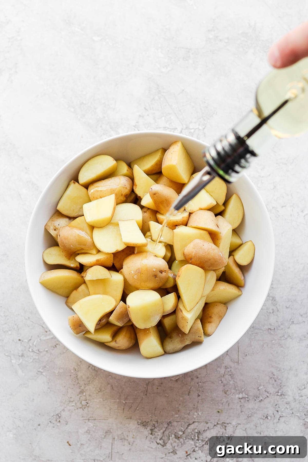 Smoked Potatoes Recipe: Crispy, Smoky Sides from the Grill 4 Oil being drizzled on cubed potatoes before being seasoned for the smoker.