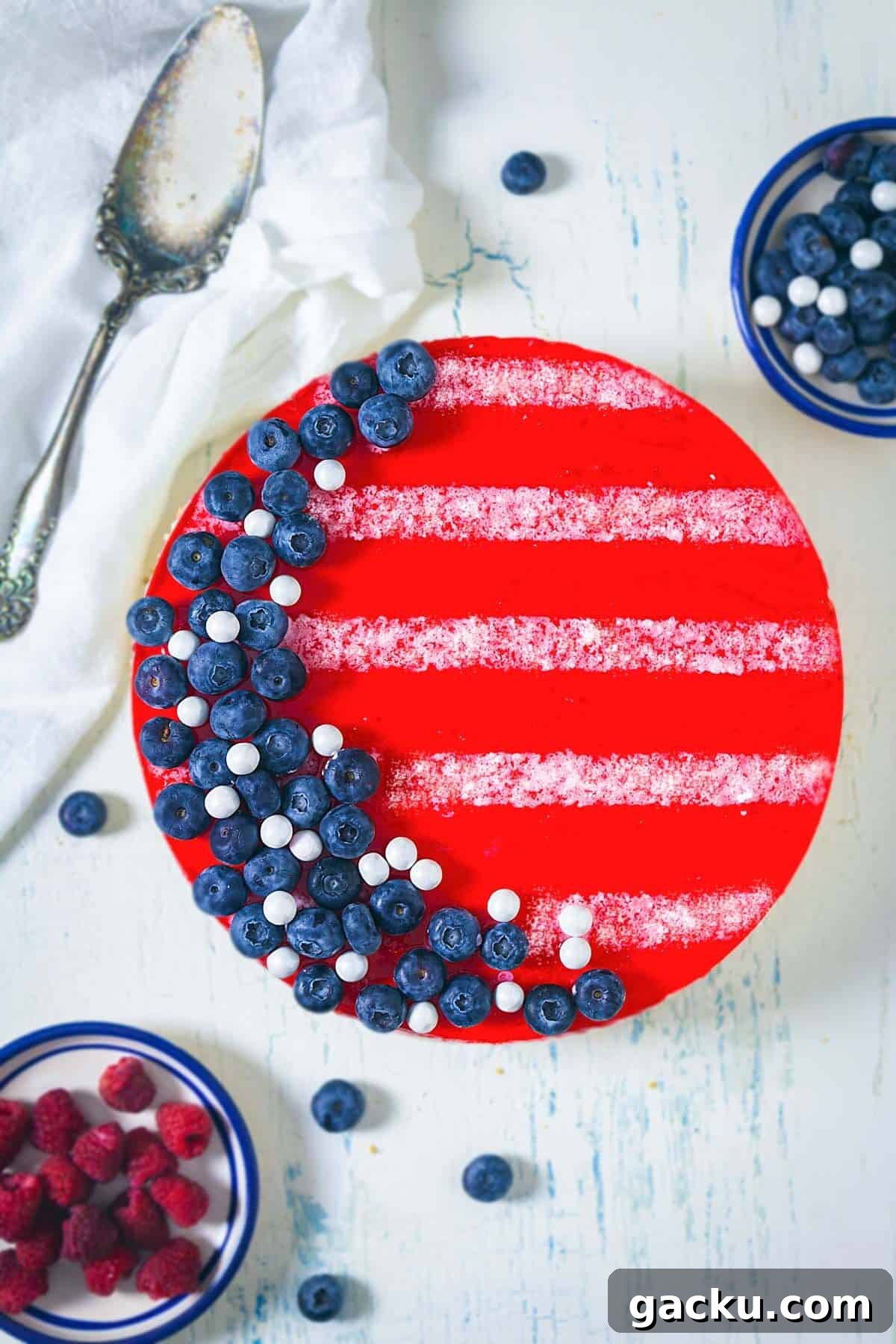 Overhead shot of red white and blue jello cheesecake showing the red top layer with blueberries and white stripes.