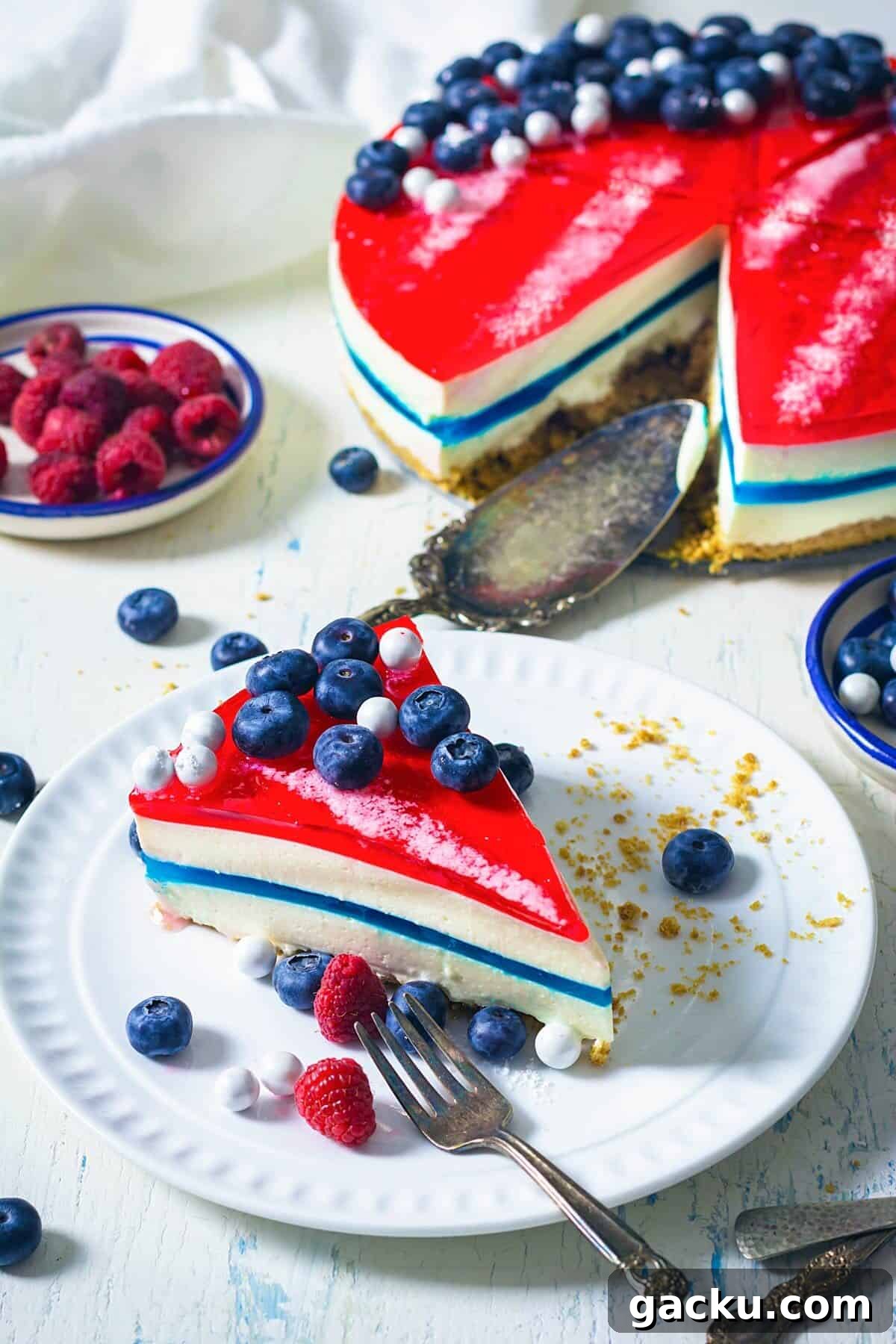 A slice of patriotic gelatin cheesecake on a white plate with fork.