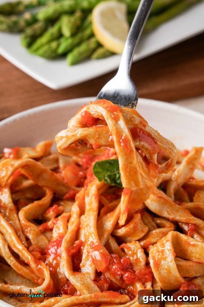 Homemade Gluten-Free Pasta Recipe—No Machine Needed 9 Gluten-free pasta in a bowl with pasta sauce and a fork taking some out.