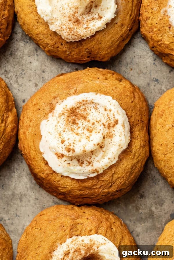 A baking sheet with pumpkin cookies topped with cream cheese frosting and cinnamon.