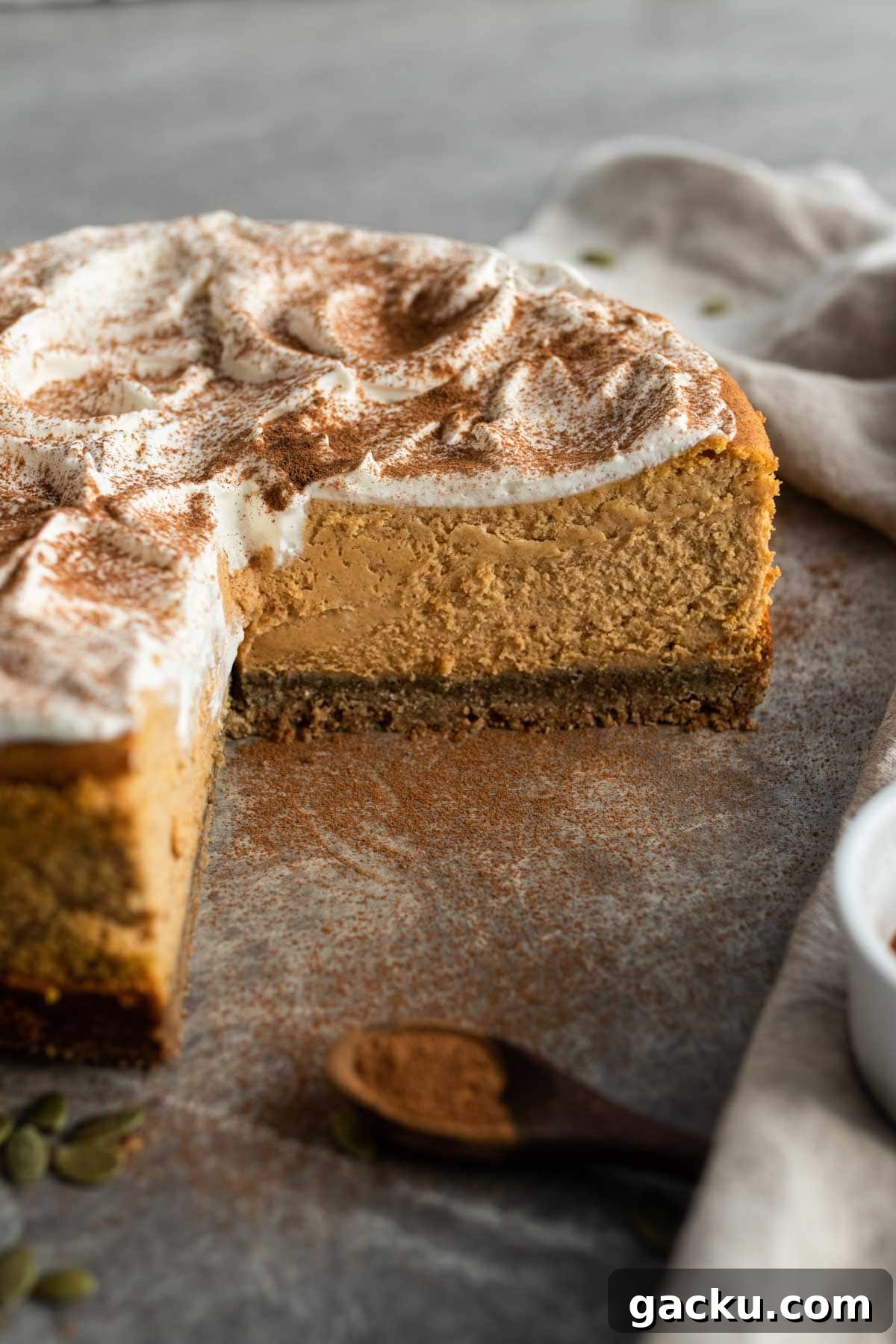 A whole cheesecake sliced with a big cut out, sprinkled with cinnamon and spices.