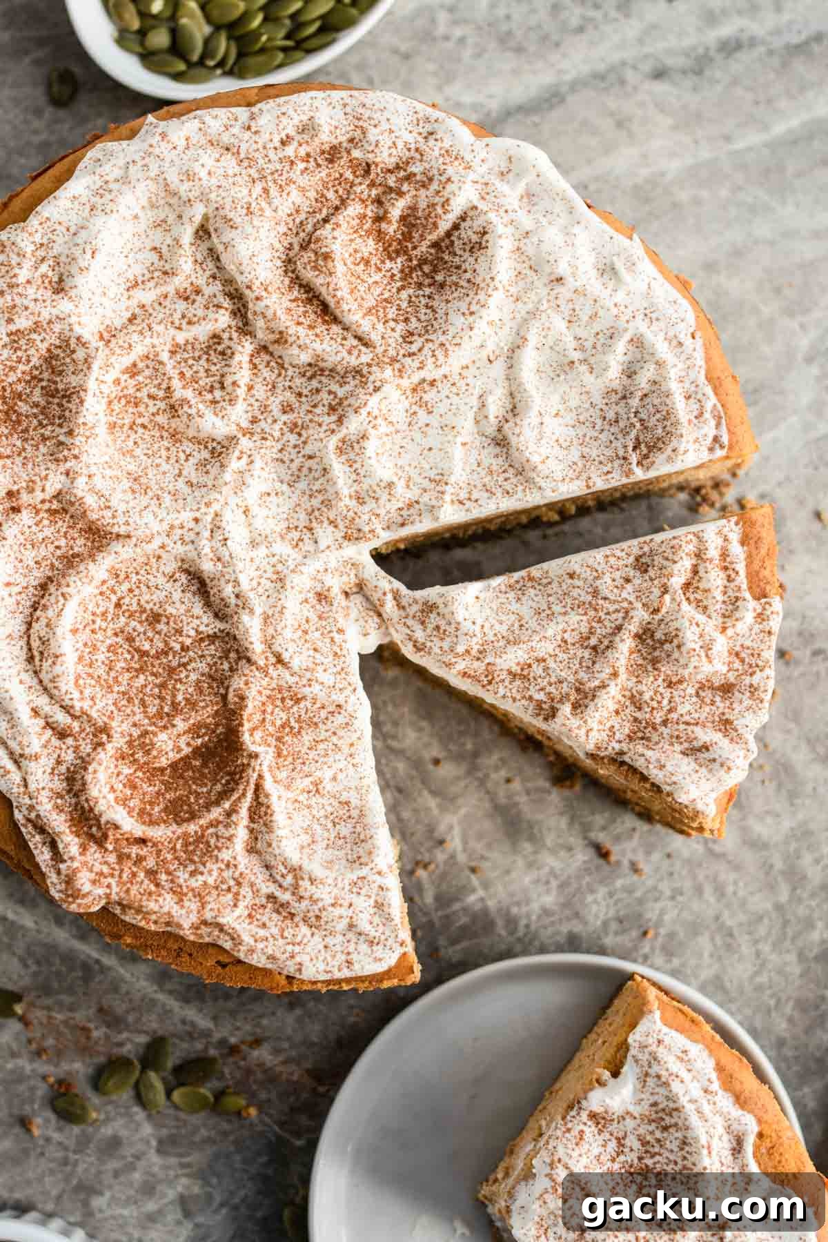A sliced pumpkin cheesecake with whipped cream and spices on top.