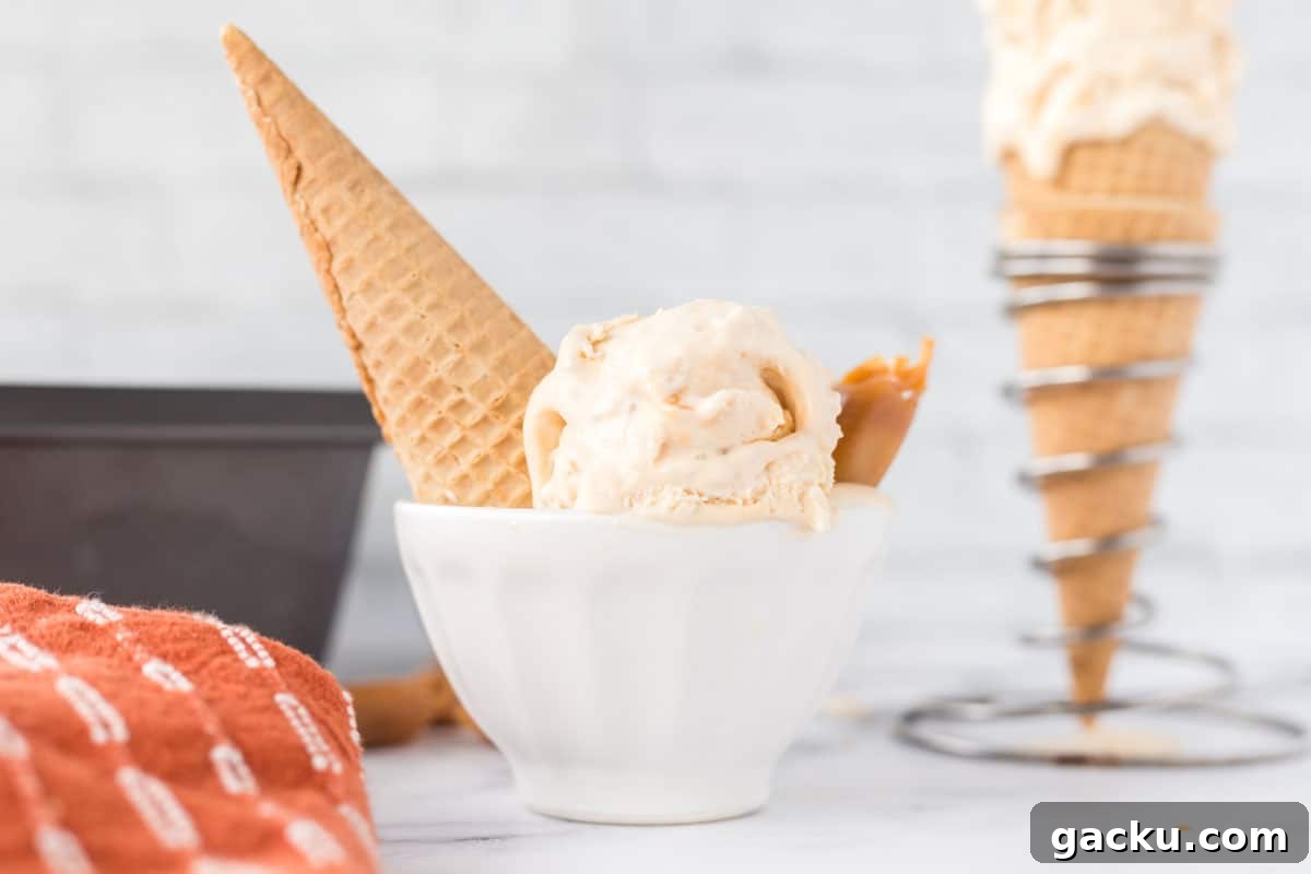 Salted caramel ice cream in a small, white bowl with a sugar cone sticking out of it.