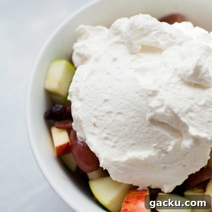 a bowl of fruit salad with a scoop of homemade whipped cream