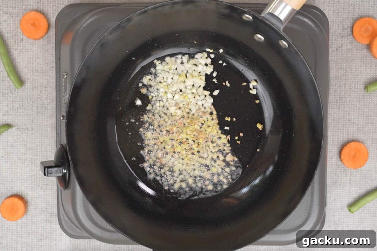 Ginger and garlic added to hot oil in a wok.