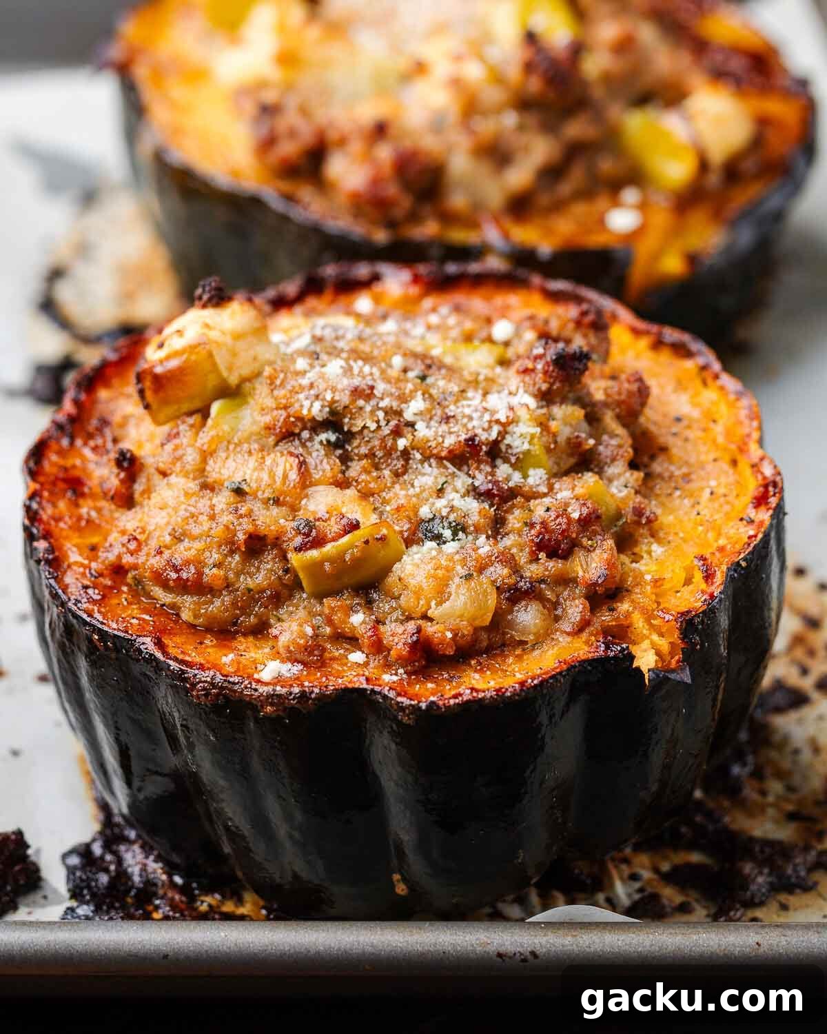 Sausage stuffed acorn squash on baking sheet.