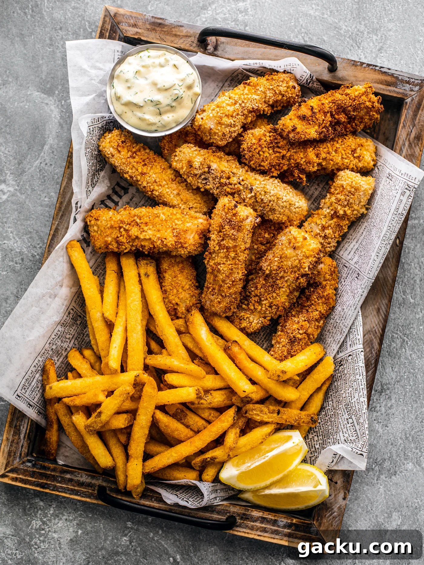 Breaded fish sticks on a serving platter with fries and lemon wedges.