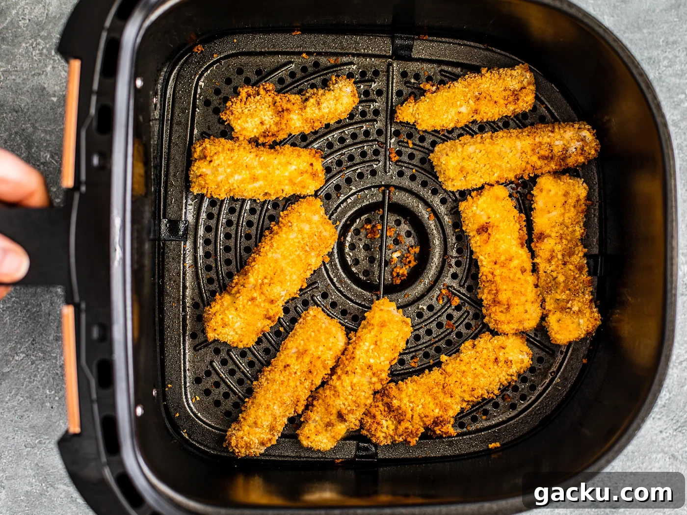 Cooked fish sticks in an air fryer basket.