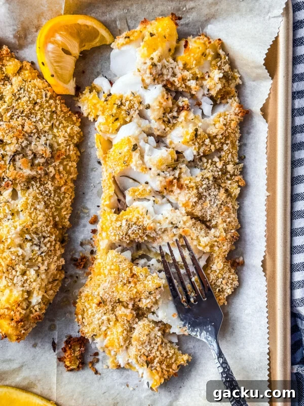 Baked Alaska pollock on a sheet pan with lemon wedges.