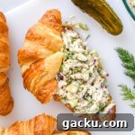 Dill Pickle Chicken Salad Recipe with Crunchy Celery & Herbs 12 dill pickle chicken salad on a croissant on a cutting board.