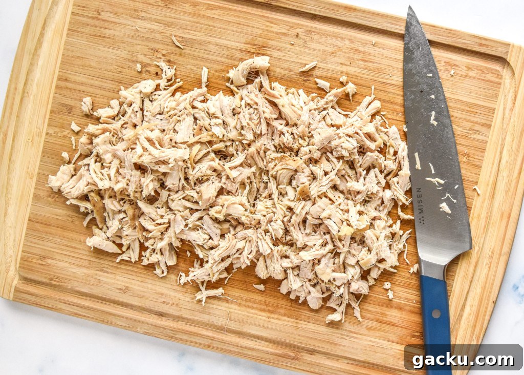 Dill Pickle Chicken Salad Recipe with Crunchy Celery & Herbs 5 chopped chicken breast on a wooden cutting board.