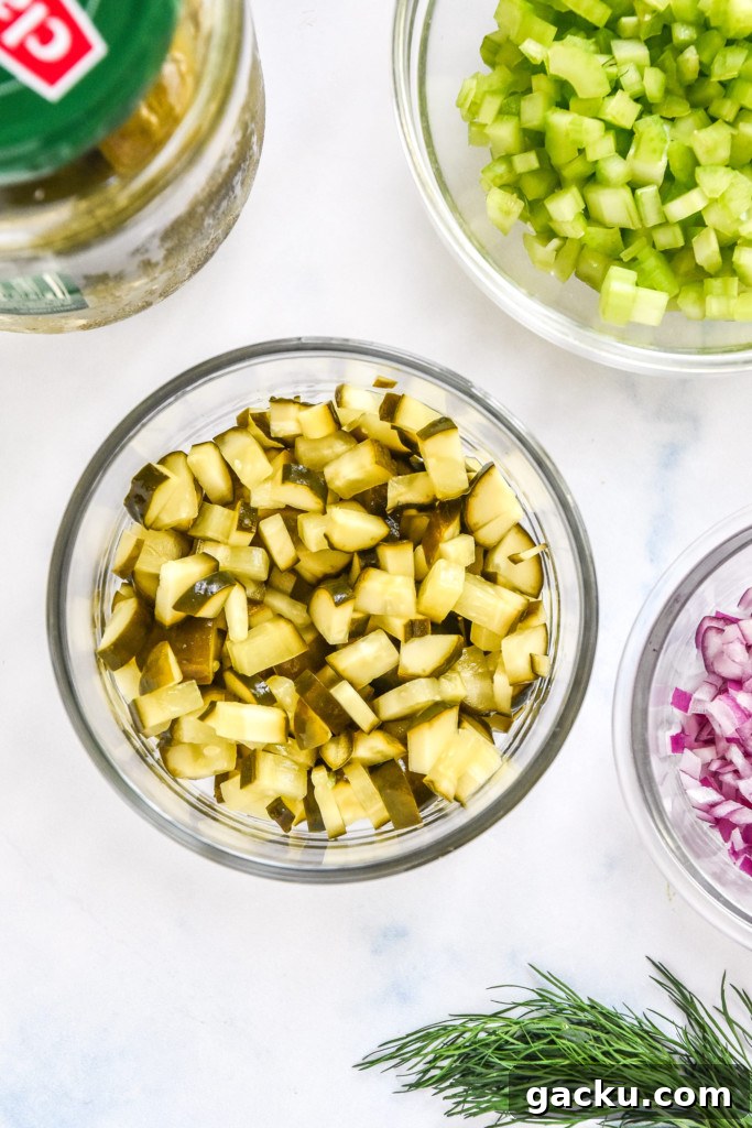 Dill Pickle Chicken Salad Recipe with Crunchy Celery & Herbs 6 diced pickles in a glass bowl.