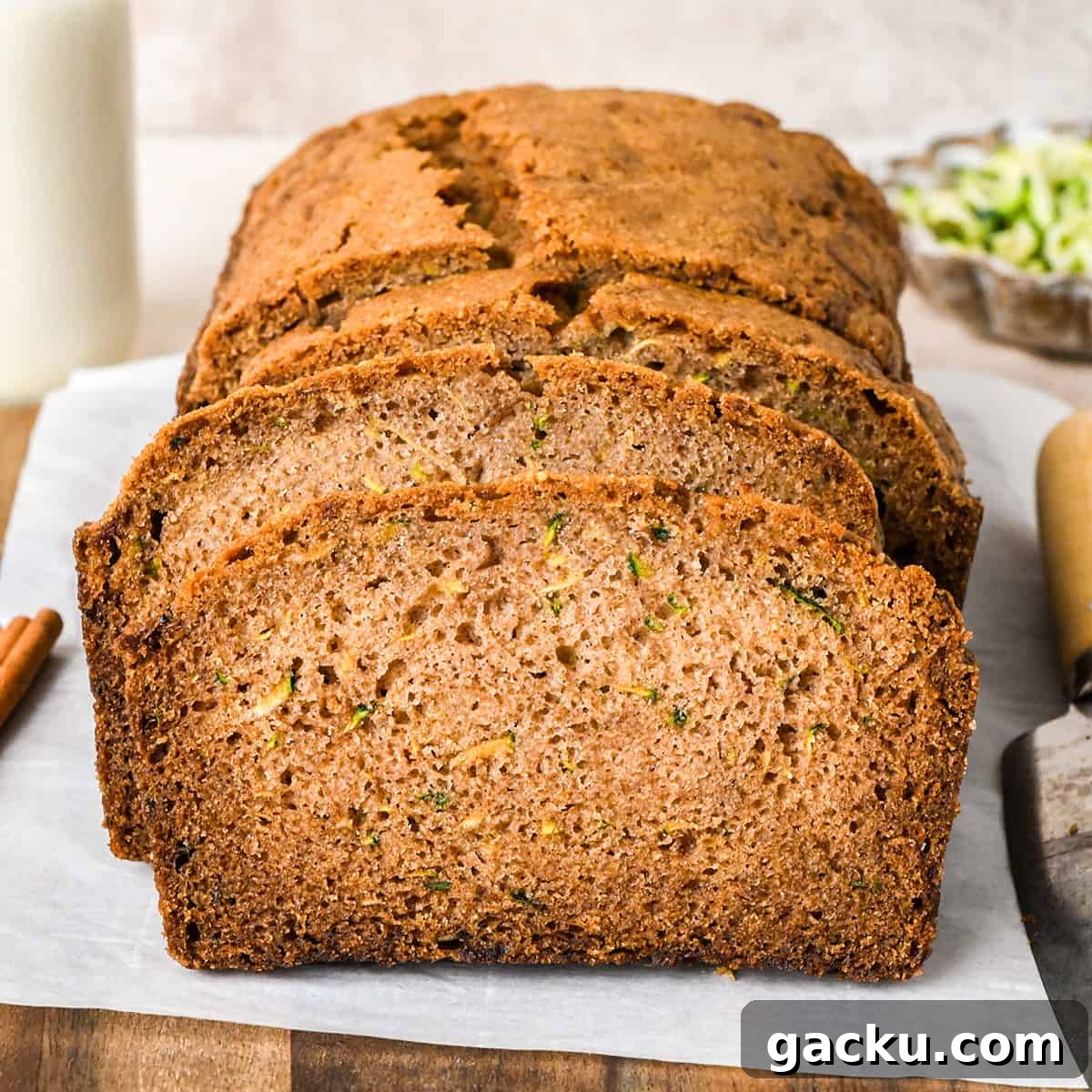 This is truly the best zucchini bread recipe! It's dense and moist with a beautiful crumb, perfectly spiced & sweet and loaded with zucchini! This easy zucchini bread comes together so fast (no mixer required) and will become your favorite way to enjoy the abundance of zucchini in the summer months! a loaf of Zucchini Bread with 3 slices cut out of it