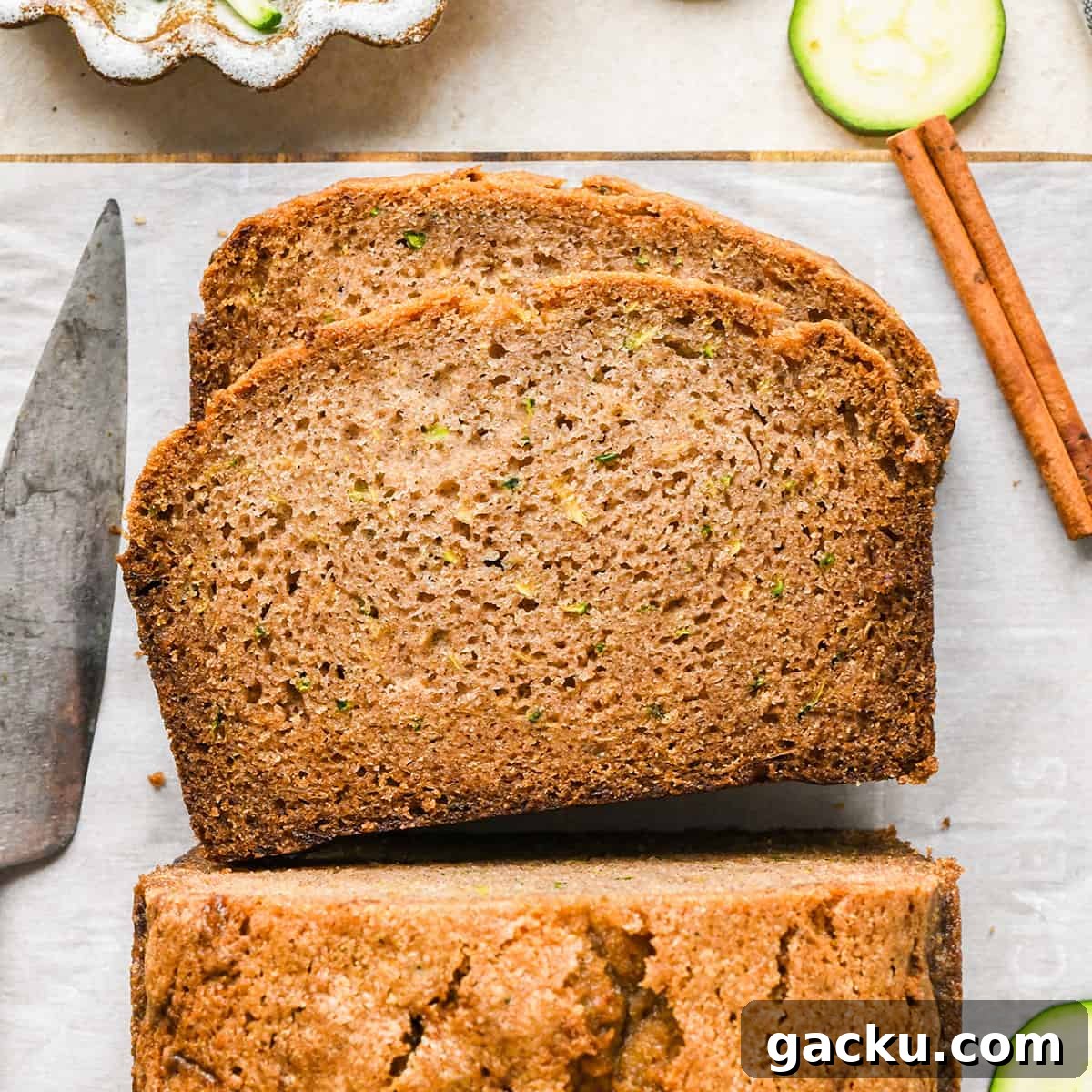 Slices of zucchini bread ready to enjoy 2 slices of Zucchini Bread laying on top of each other on a cutting board near the loaf