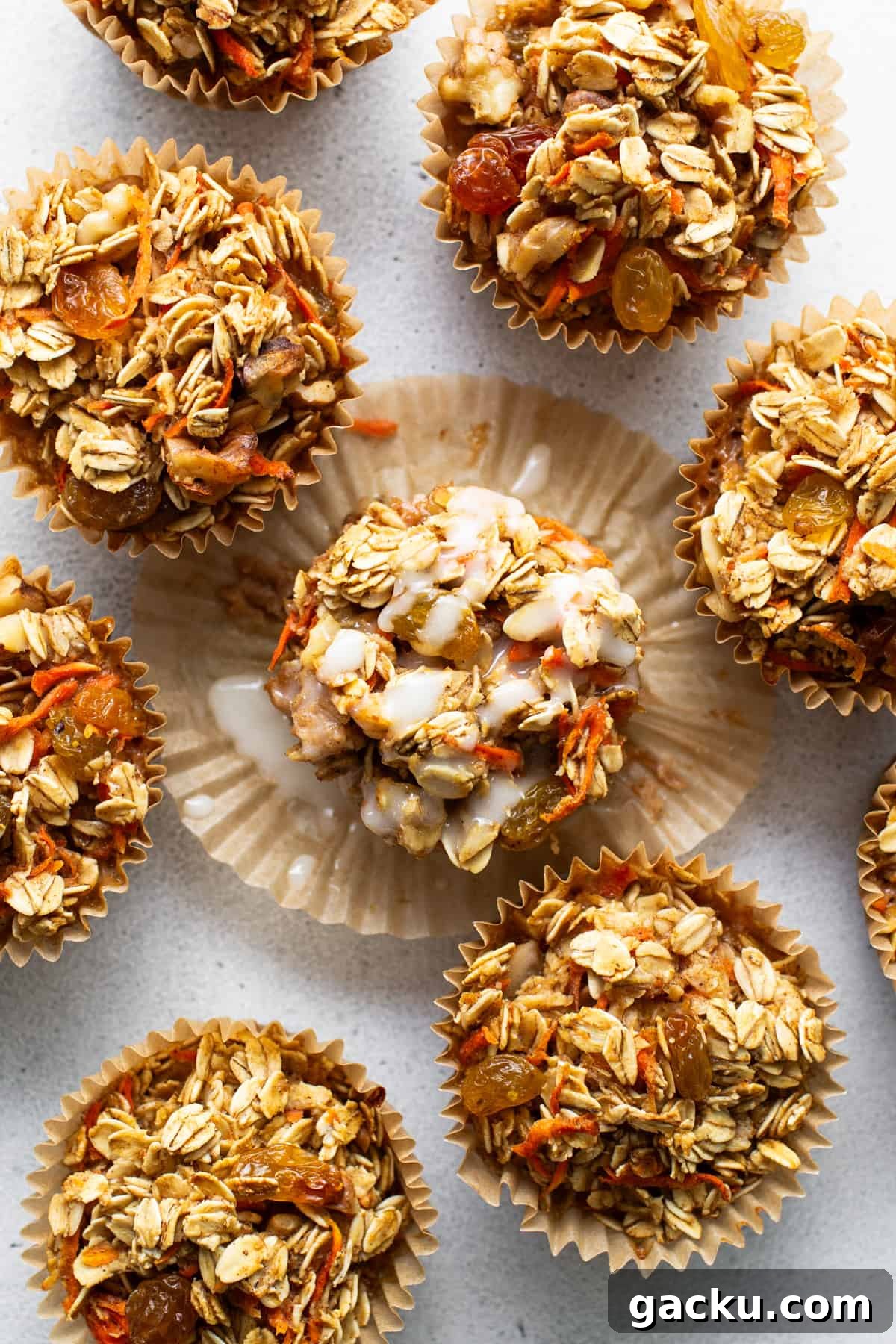 Carrot Cake Oatmeal Muffins: Spiced Breakfast Cups with Raisins and Nuts 4 A group of granola muffins on a white surface.
