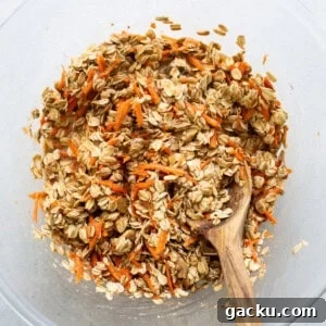 Carrot Cake Oatmeal Muffins: Spiced Breakfast Cups with Raisins and Nuts 8 Oats in a bowl with a wooden spoon.