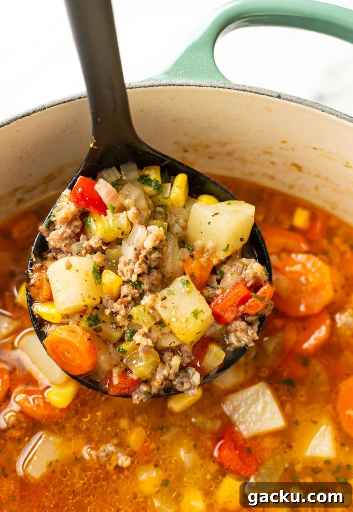 a ladle with italian sausage vegetable soup