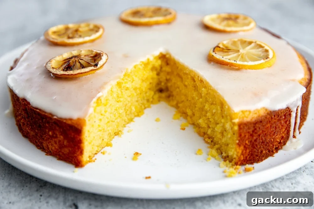 The lemon olive oil cake on a platter with a large wedge cut out.