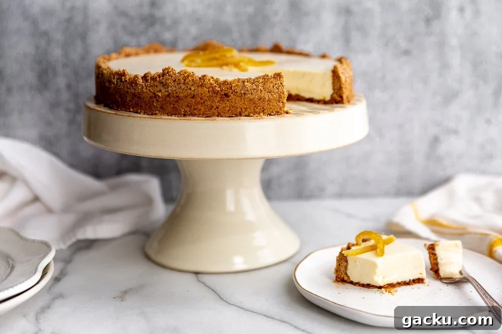Creamy lemon pie with almond crust on cake stand, with a piece of pie on a plate.