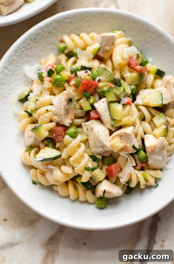 close-up of creamy Pasta Primavera with chicken and fresh vegetables in a white bowl