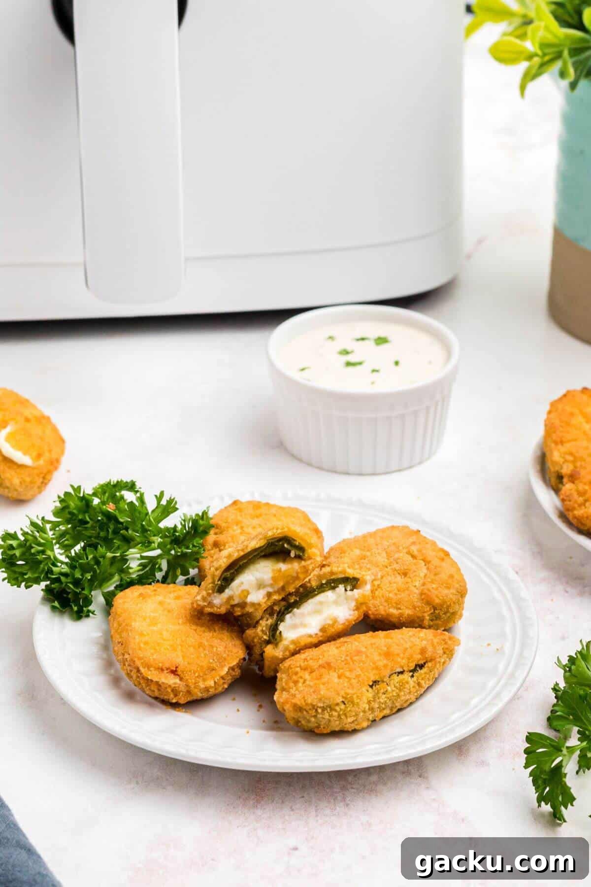 Golden crispy breaded jalapeno poppers on a small white plate. 