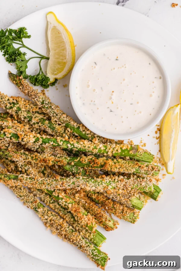 Plated air fried asparagus fries with lemon wedges and dipping sauce.