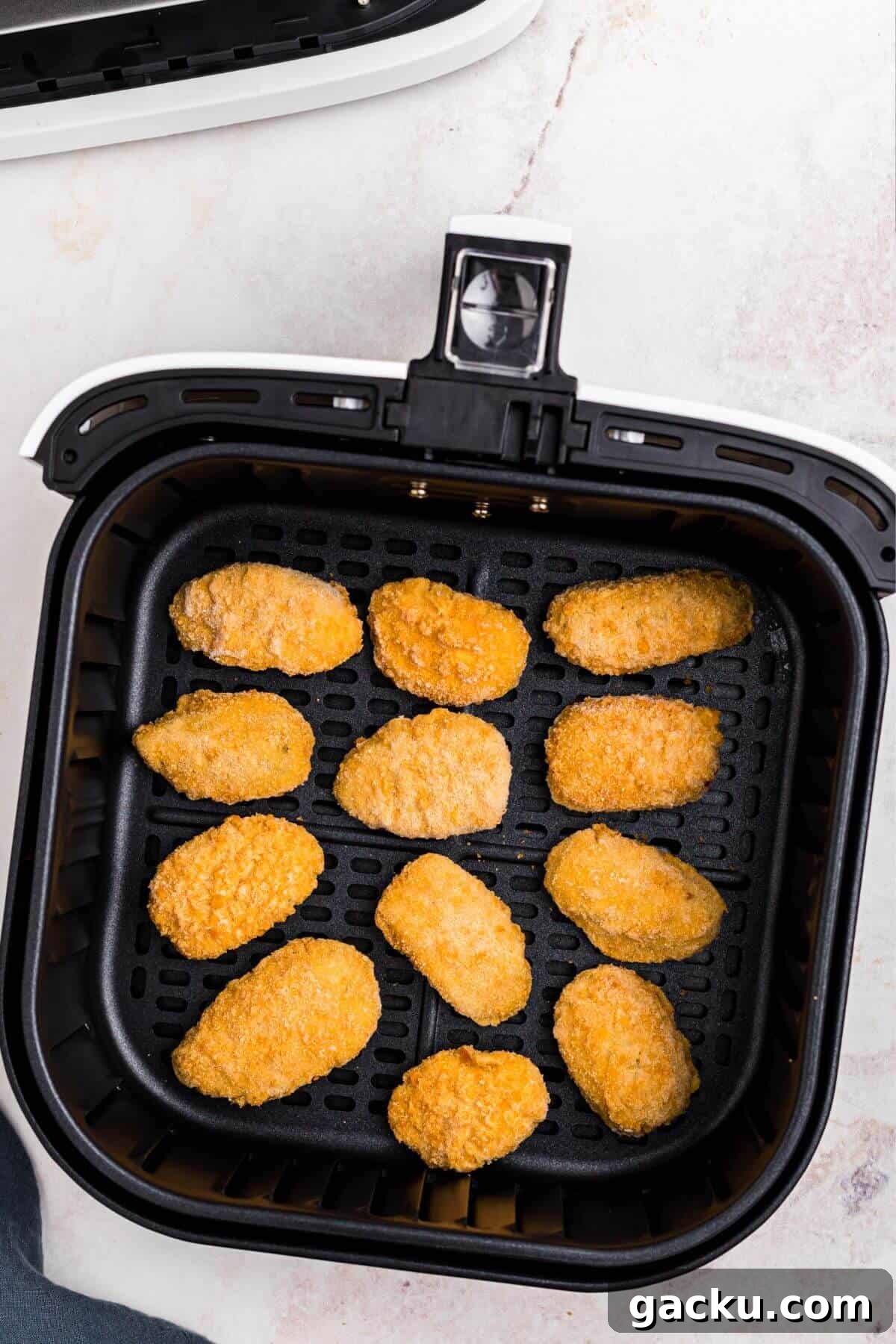 Frozen jalapeno poppers in an air fryer basket before being cooked. 