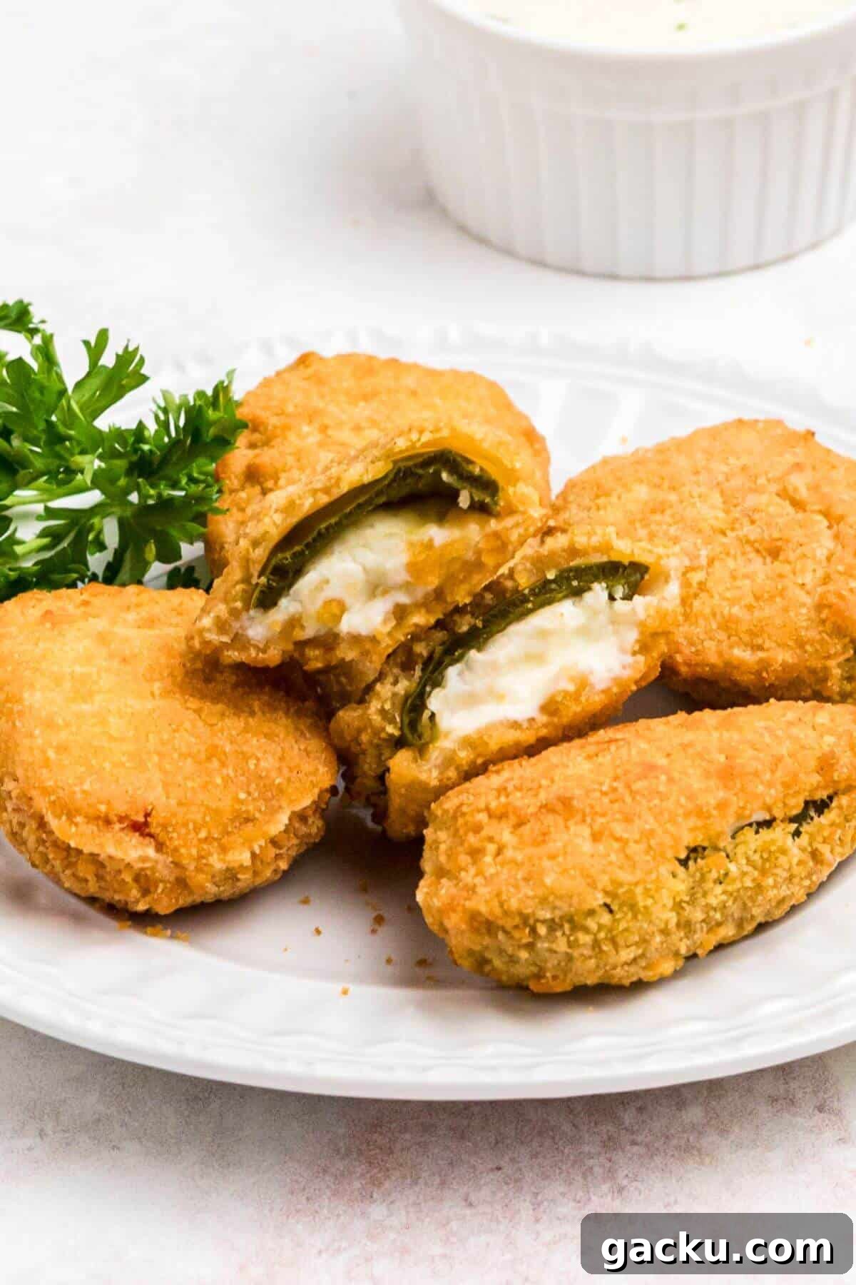 Golden crispy breaded jalapeno poppers on a small white plate.