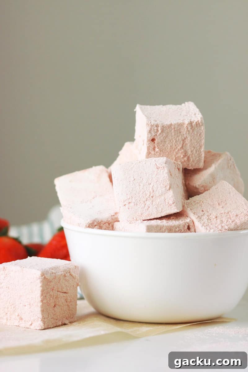 a bowl of homemade strawberry marshmallows with fresh strawberries