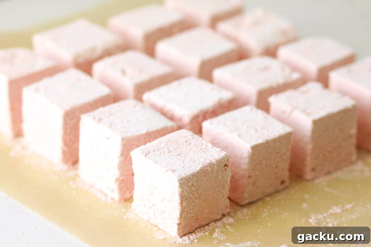 homemade strawberry marshmallows lined up on parchment paper