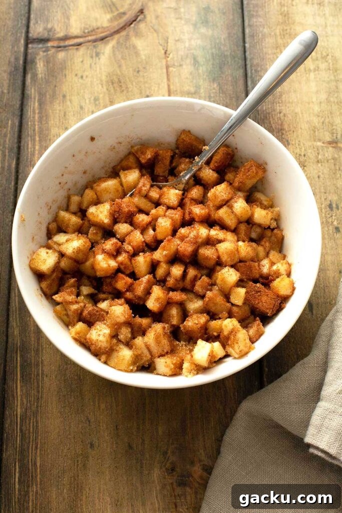 Cinnamon Apple Quick Bread Recipe for Moist, Spiced Loaf 6 Diced apples tossed with brown sugar and cinnamon in a white bowl