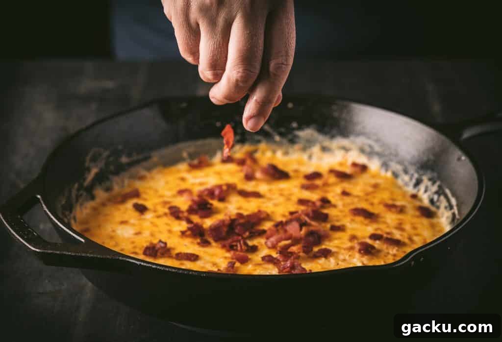 Skillet Bacon and Smoked Cheese Dip Recipe 4 Bacon being added to a skillet of smoked cheese dip.