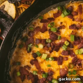 Smoked queso in a cast iron skillet topped with bacon and green onions.