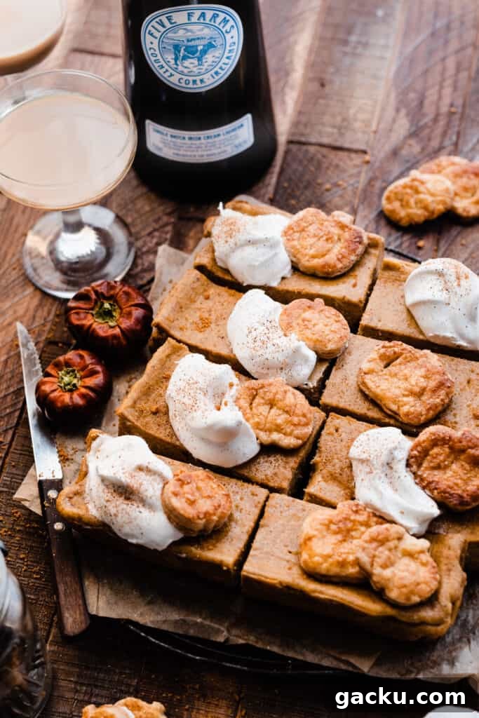 Irish Cream Pumpkin Cheesecake Bars Recipe for Fall Desserts 10 A birds eye view of the sliced pumpkin bars topped with whipped cream on a wooden surface, with glasses of irish cream.