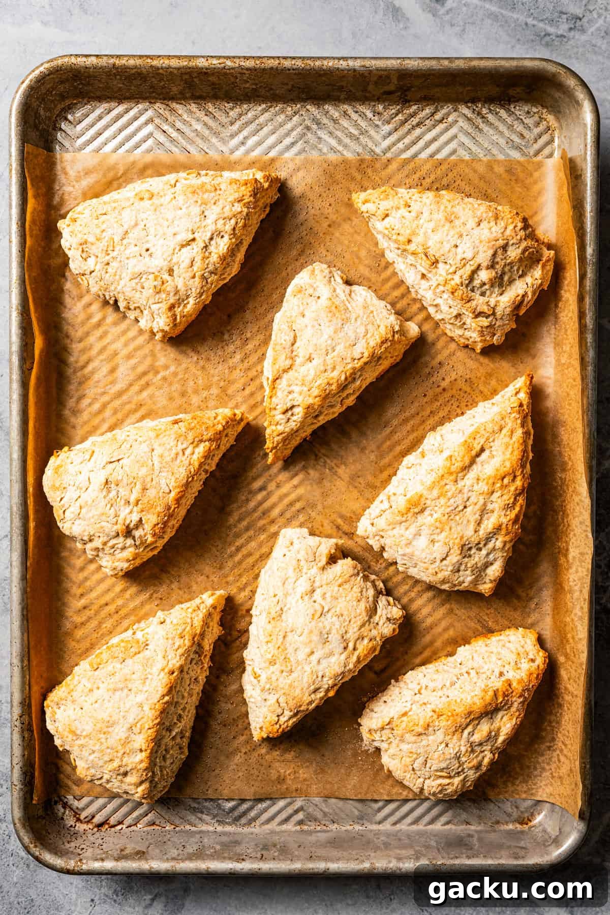 Bake! Baked cinnamon scones on a parchment-lined baking sheet.