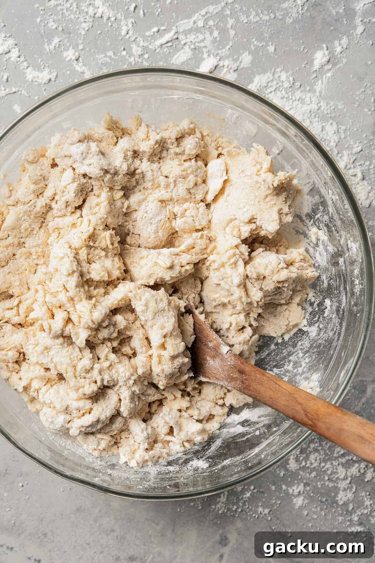 Mix the dough. Cinnamon scone dough coming together in a glass mixing bowl with a wooden spoon.