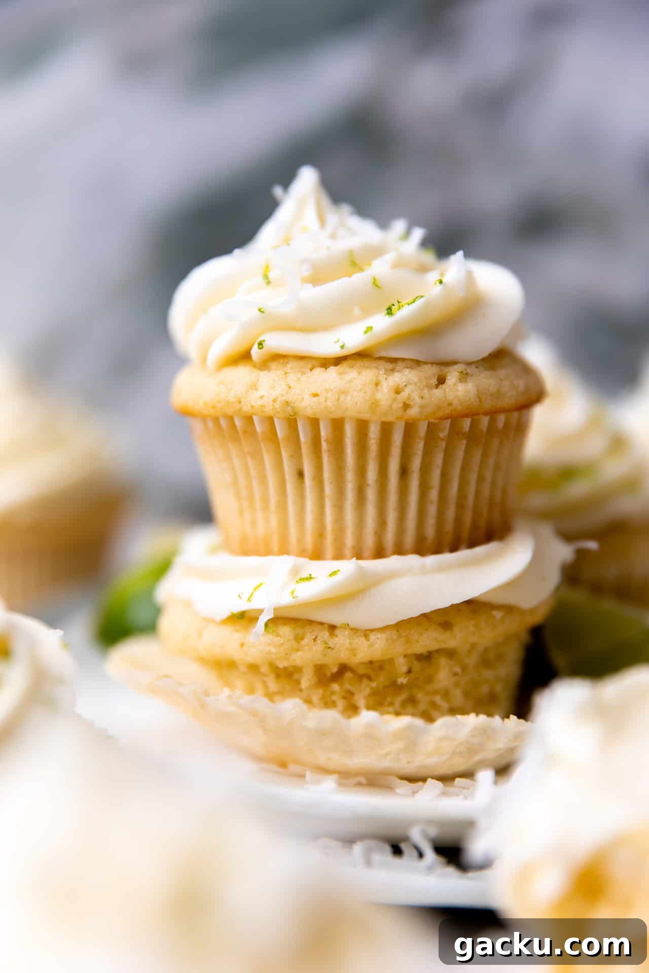 Coconut Lime Cupcakes with Creamy Coconut Frosting 2 Stacked coconut lime cupcakes topped with coconut cream cheese frosting.