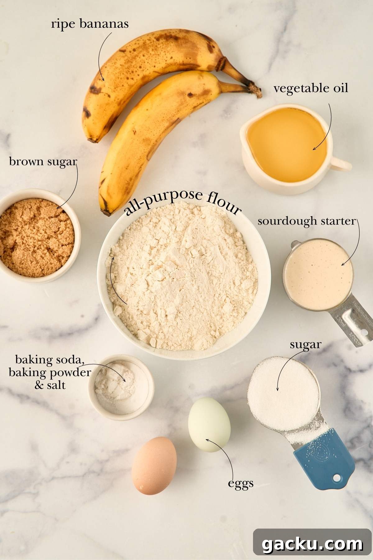 Moist Spiced Sourdough Banana Cake Recipe for Tangy Flavor 3 Overhead view of sourdough banana cake ingredients labeled and arranged on a marble surface.