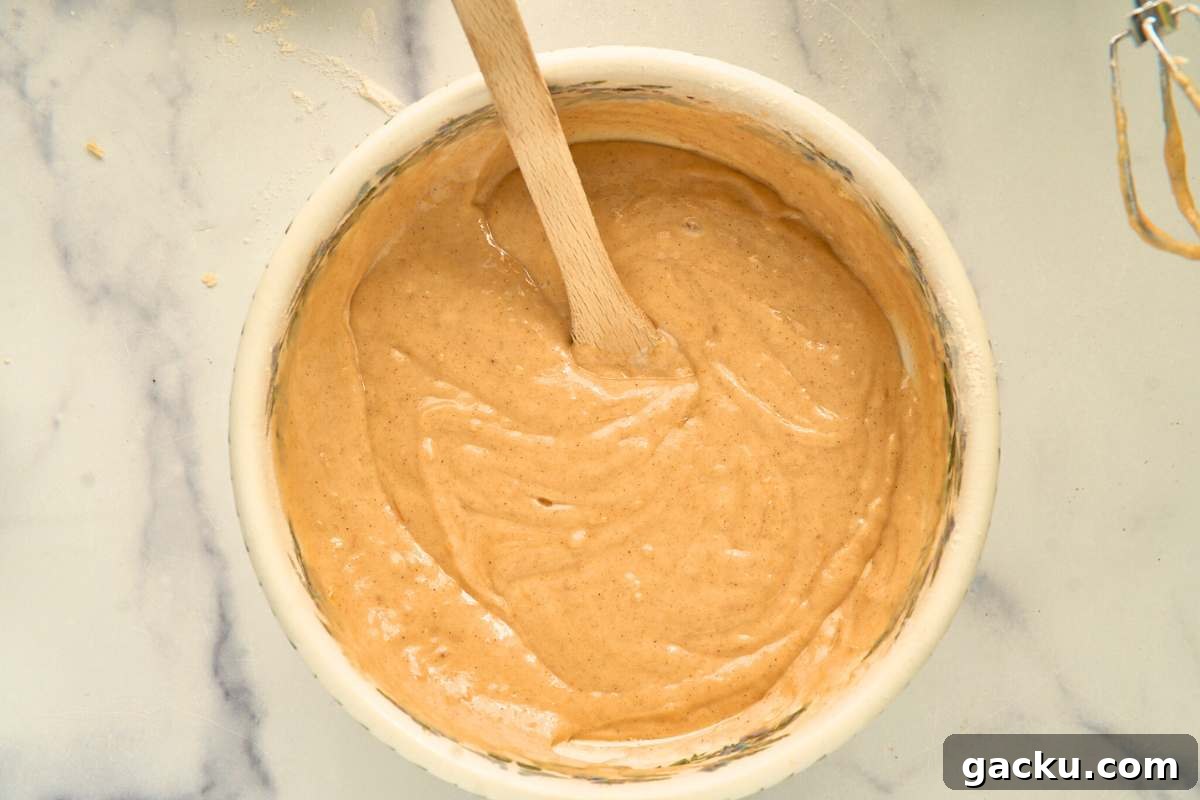 Moist Spiced Sourdough Banana Cake Recipe for Tangy Flavor 6 Smooth cake batter in a mixing bowl with a wooden spoon resting inside